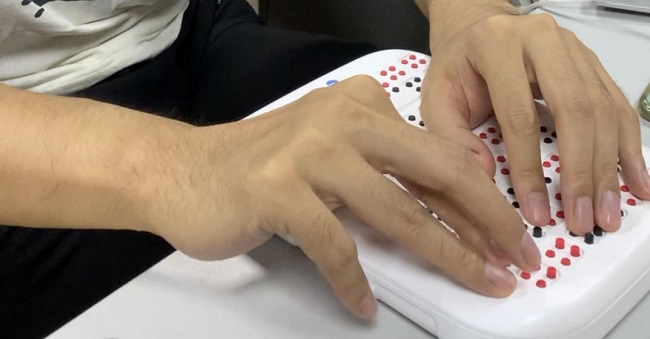 图为视障学生试用盲用分数辅助运算器样机